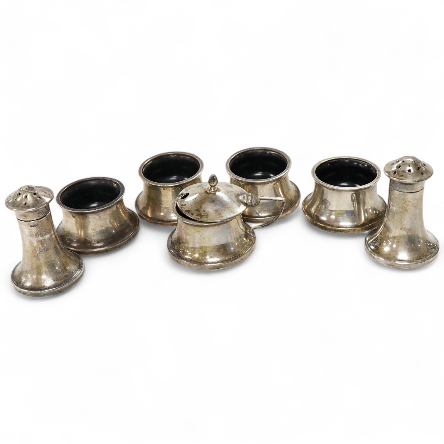 A George V seven piece silver mounted condiment set, by Joseph Gloster Ltd, Birmingham, 1932, pepper 65mm (a.f.).